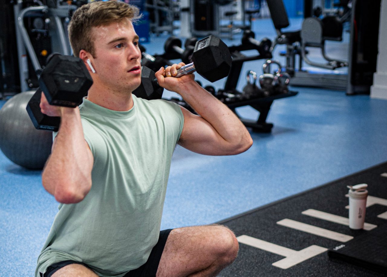 Man performing a thruster exercise using the Fiit workout app