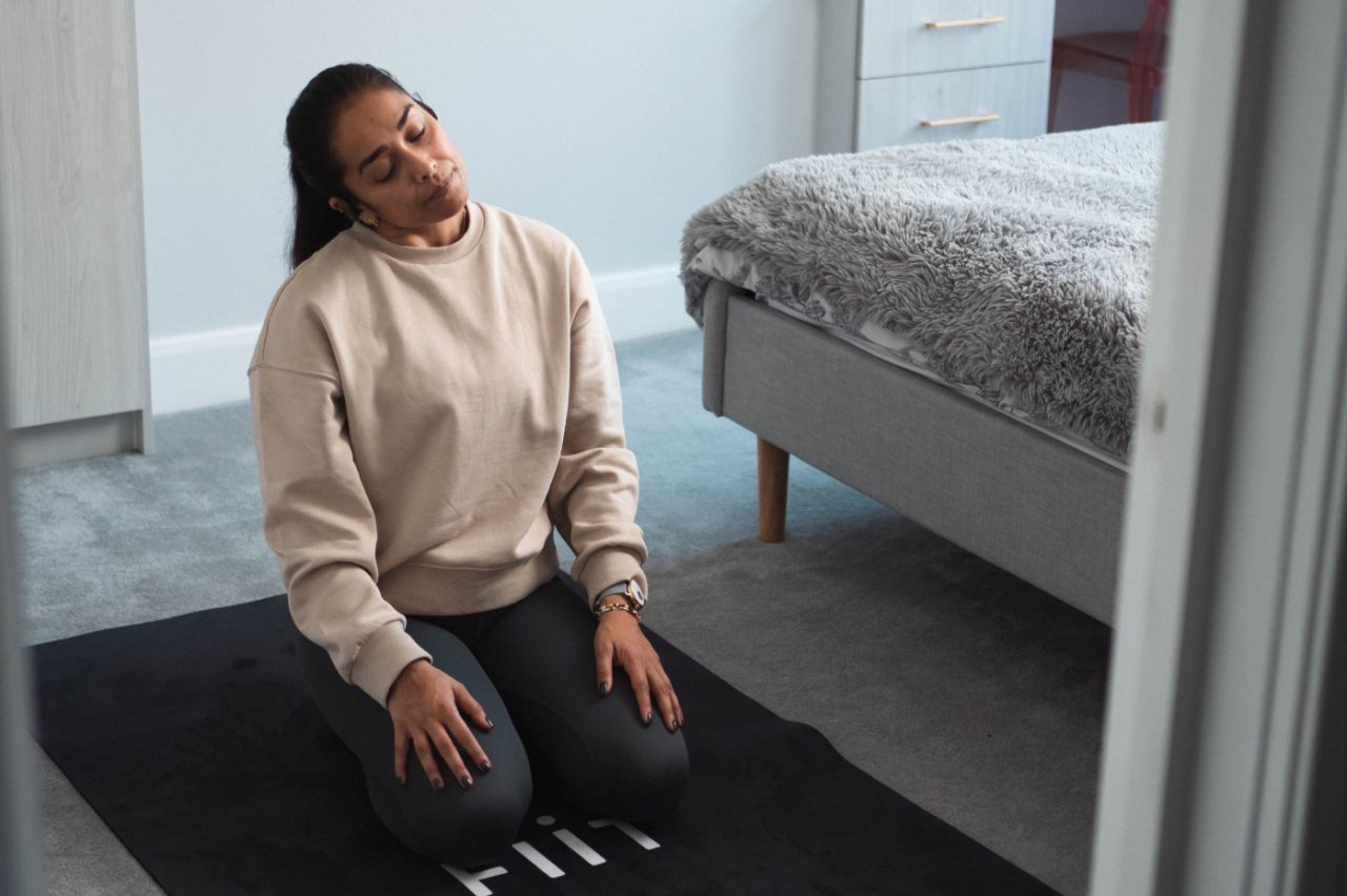 Woman stretching on a yoga mat preparing to do a Fiit workout