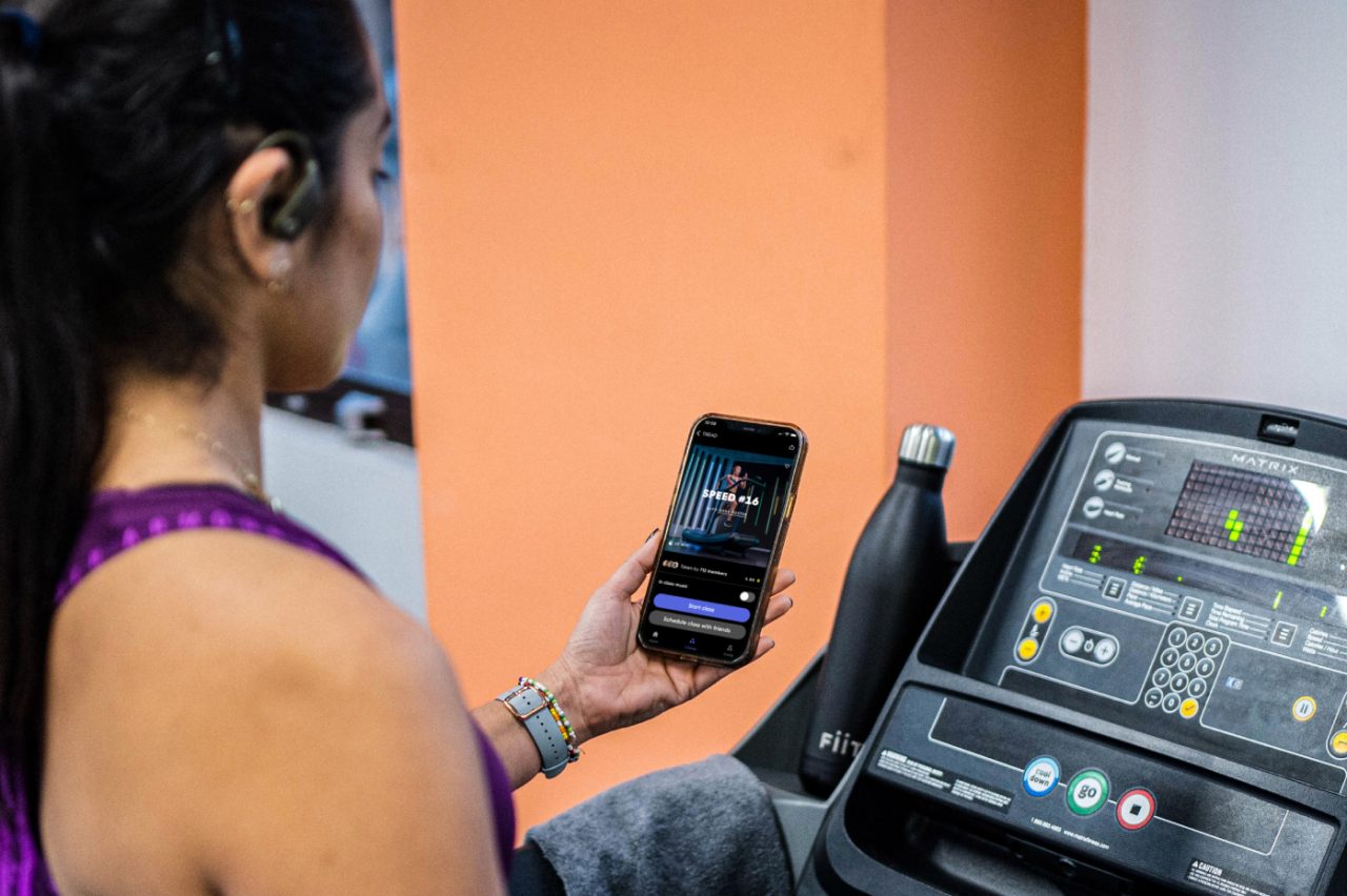 Woman pairing her mobile with a treadmill preparing to do a Fiit workout